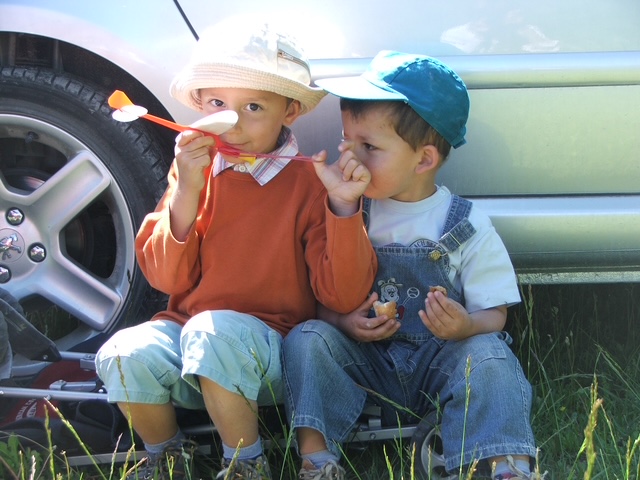 Robin et Justin enfants, complices, assis contre une voiture